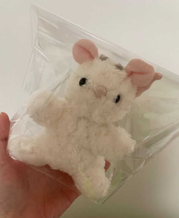 白いふわふわのネズミのぬいぐるみの写真。包装されている様子。