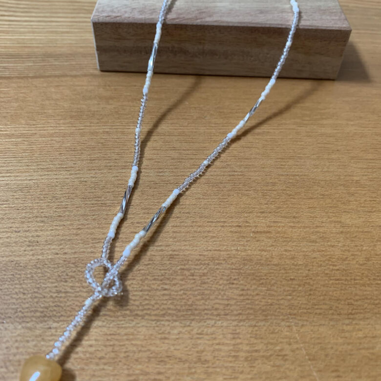 白、シルバー、クリアビーズで作ったネックレスのトップにハートのモチーフがついています。長さがあり、くるりとひと巻きしてもオシャレ