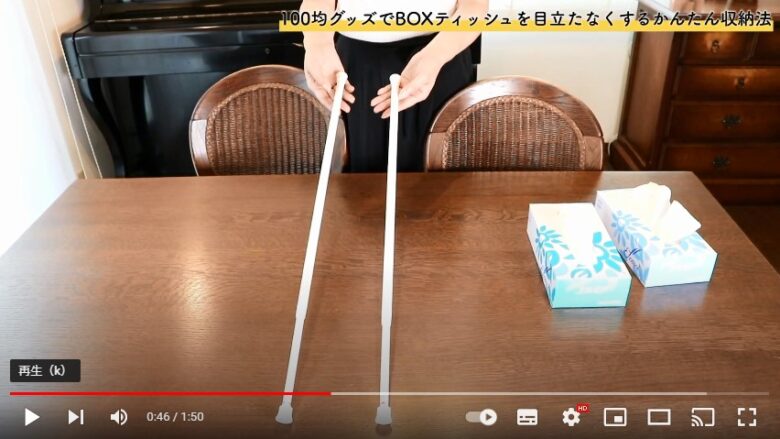 ダイニングテーブルの上に、長さ１メートル、直径12ミリから13ミリ程度の細い二本の突っ張り棒を並べて、その脇には二つのBOXティッシュが置いてあります。