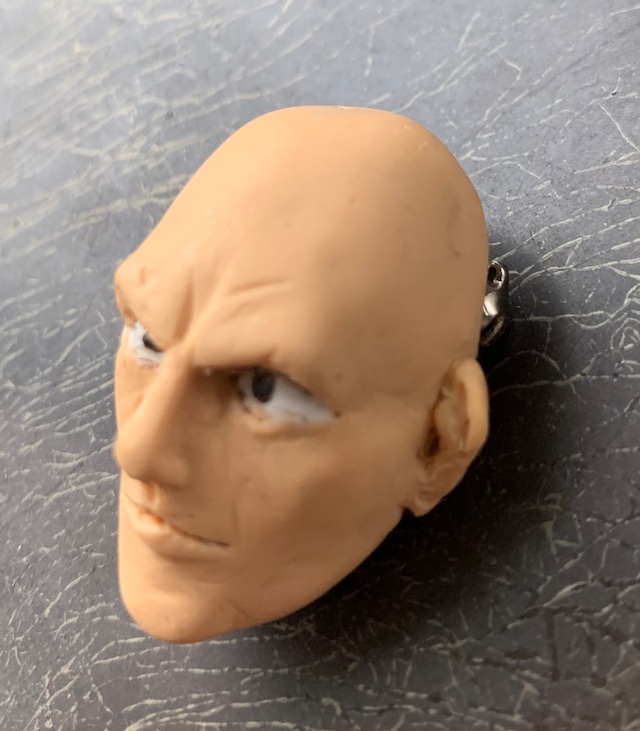 スキンヘッドの男性の顔を模した樹脂粘土製ブローチの画像。強面だが頼りがいのある顔立ちが印象的。