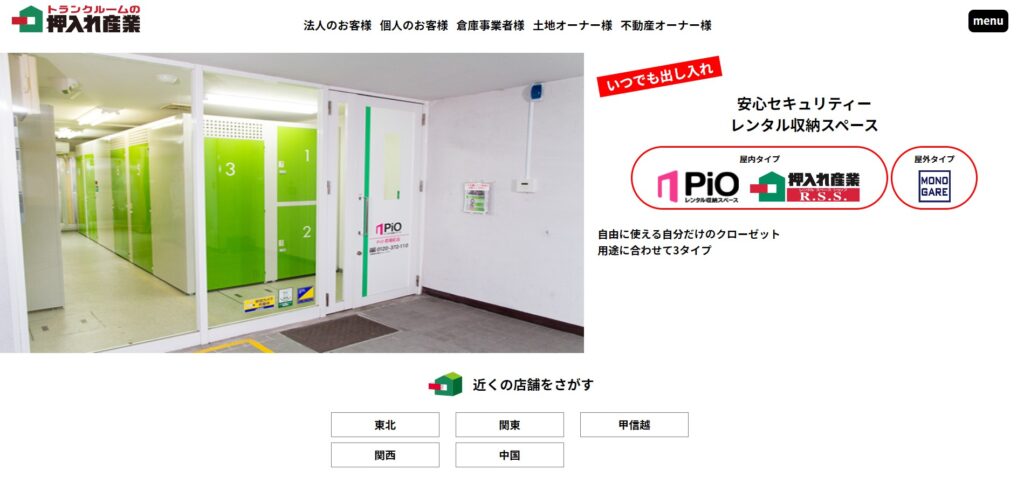 押入産業のピオという屋内型トランクルームの紹介ページです。ピオの正面玄関が写っていて、ガラス張りの扉の向こう側には、明るい緑色の扉のトランクルームが何個も並んでいます。