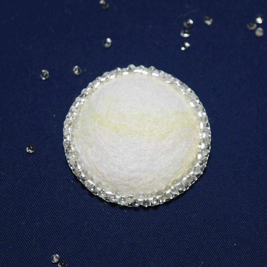 白い羊毛フェルトを使った半球状のブローチの画像