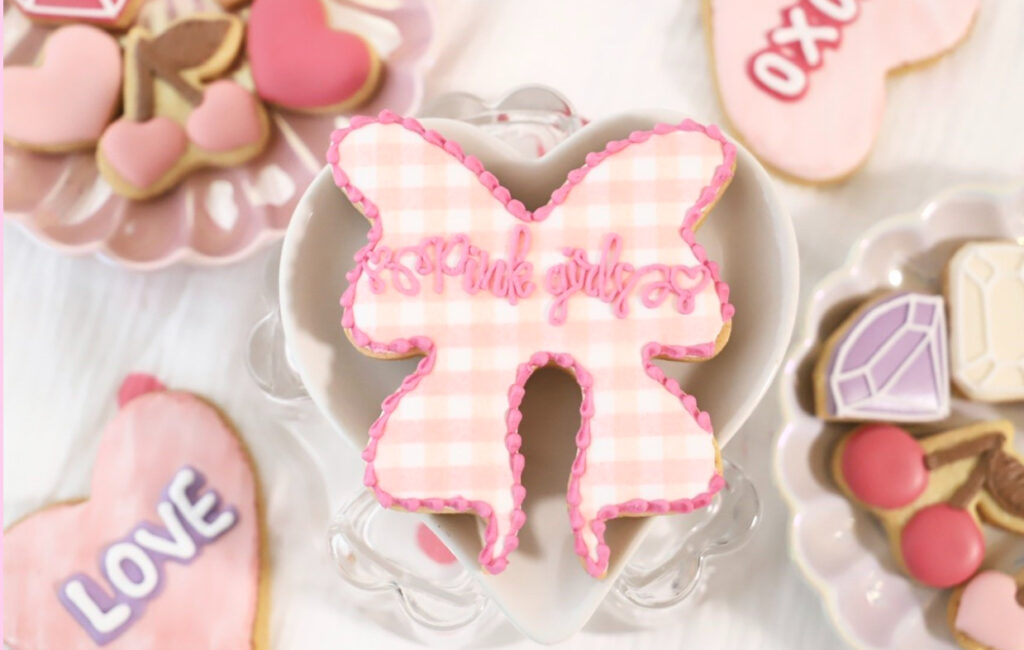 宮下まいさんのショップpink girls !!!のトップ画像、お皿にハートやサクランボ、リボンのクッキーが置かれている。真ん中のリボンのクッキーにショップ名が書かれている。