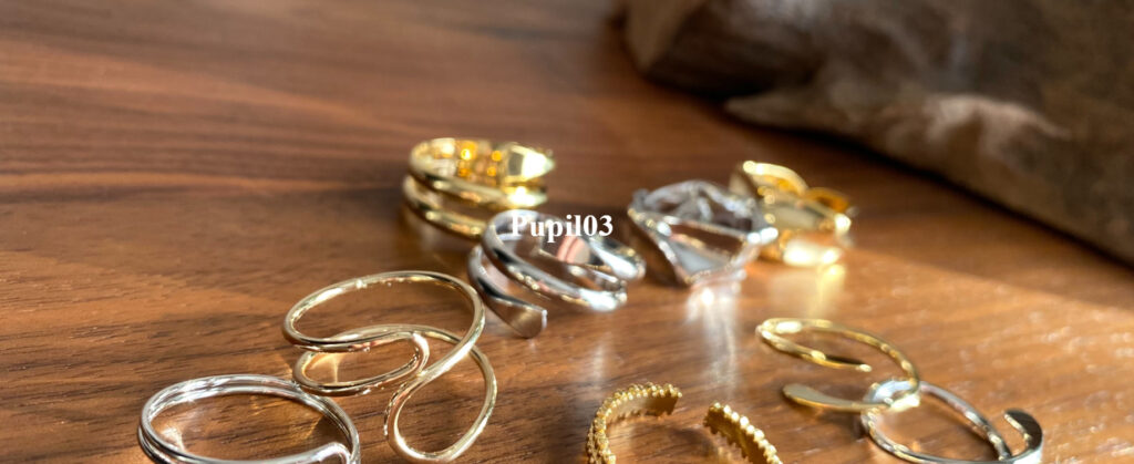 瀧澤瞳さんのショップPupil03のトップ画像、テーブルの上にシルバーやゴールドの指輪がたくさん並んでおり、そこにショップ名が書かれている