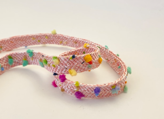 ピンクの紐で編まれた帯紐には、黄色や紫、ブルー、緑のカラフルな糸がついている