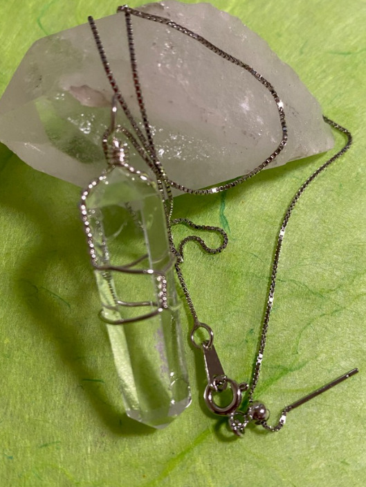 水晶の上にシルバーのチェーンがついた透明水晶のネックレスが置かれている
