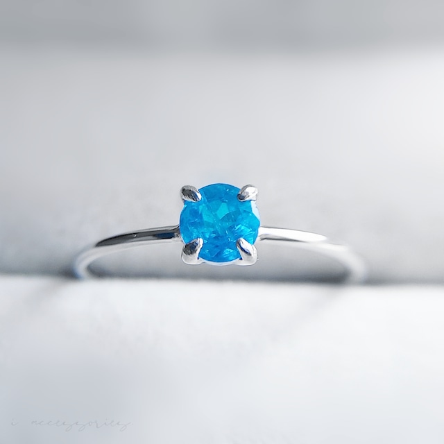 細身のシルバーカラーのリングに、ラウンドカットの鮮やかなブルーのアパタイトがセットされた指輪作品の画像。