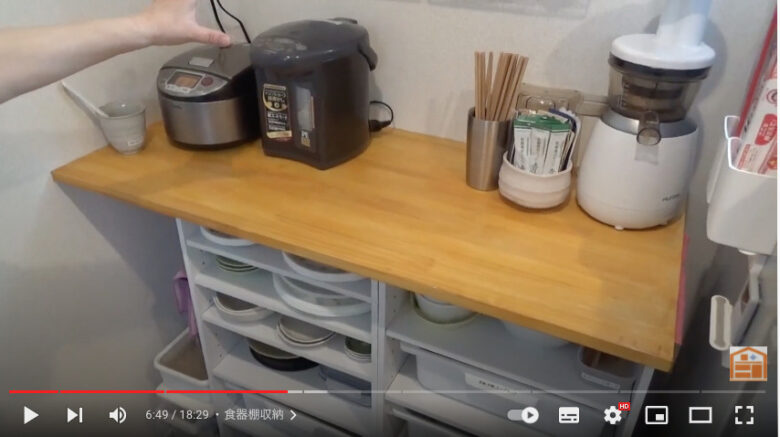 整理収納アドバイザーの片付けお母さんが、見直した食器棚について解説している写真。食器棚の上には、炊飯器、ポット、箸などが置かれている。