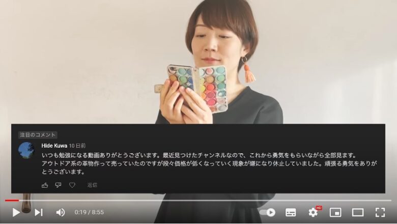 画面中央に、スマホを両手で開き、スマホを見ている齋藤貴栄さん。画面の下三分の一位のところには、黒い幅の広い帯があり、そこに白抜きの文字で、齋藤貴栄さんの動画チャンネルに投稿されたコメントが掲載されています。