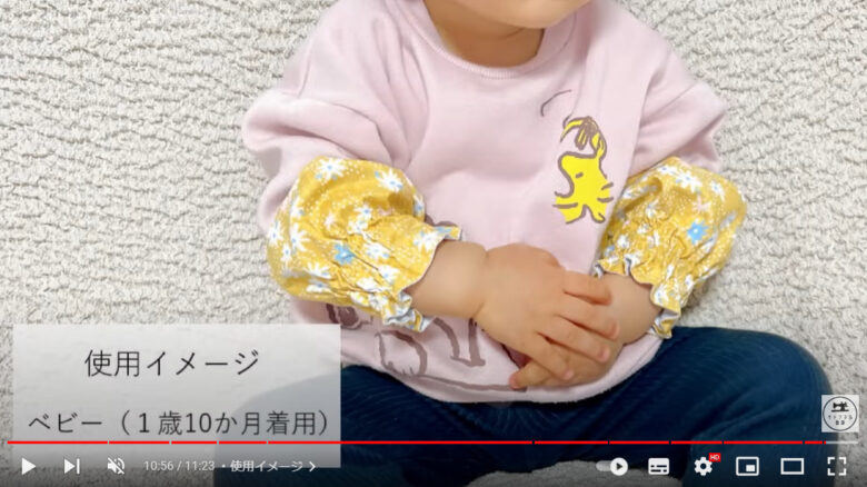 座っている子供がアームカバーを両腕に着用している様子。「使用イメージ、ベビー(1歳10か月着用)」と書かれている。