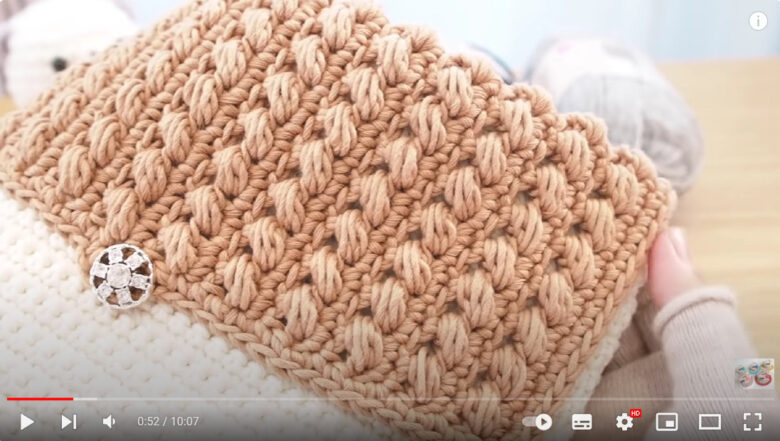 「斜めに走る玉編み模様」のクラッチバックを紹介しています。色はライトベージュ。マッシュは顔が半分バックで隠れてます。