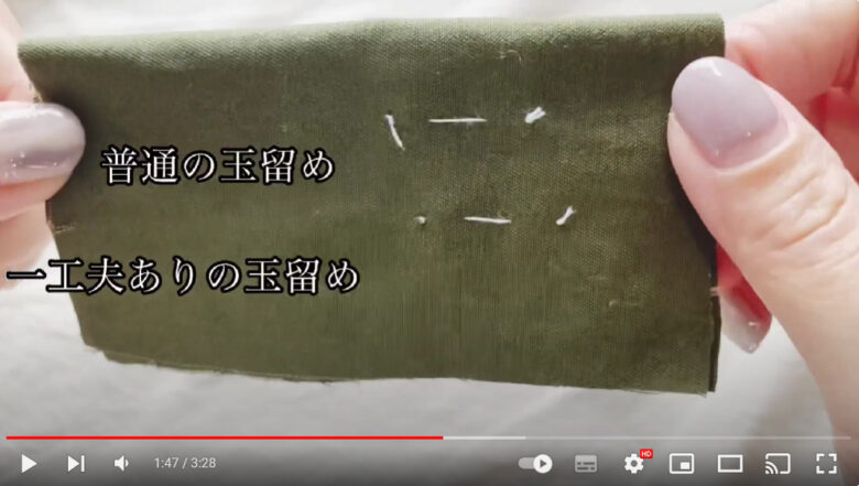 工夫ありの玉留めのメリットについて話す場面。画面では、深緑色の布にある玉留めを、はさみで示している様子が映り込んでいる。