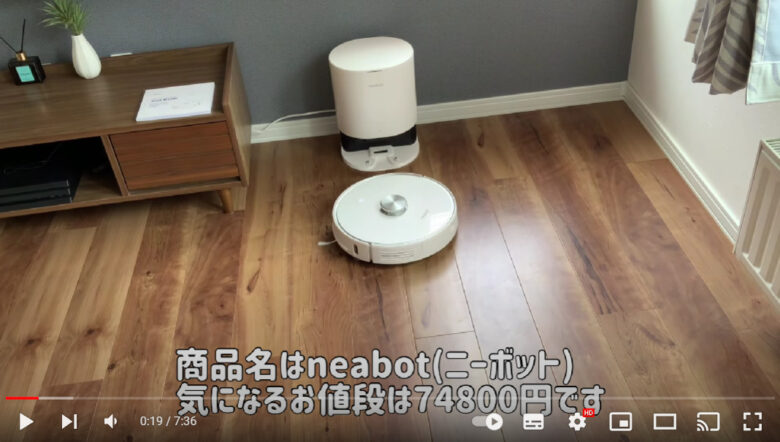部屋の一角に、ロボット掃除機が置かれている。本体は白く丸い。ホーム部分も白く、楕円形をしている。