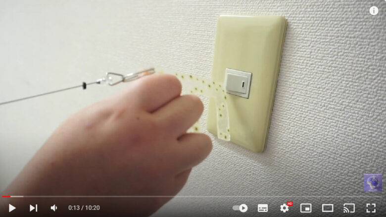 サンシャインさんが自分で作ったプラ板のドアオープナーを使って、電気のスイッチを入れている画像です。
花柄のかわいいドアオープナーです。